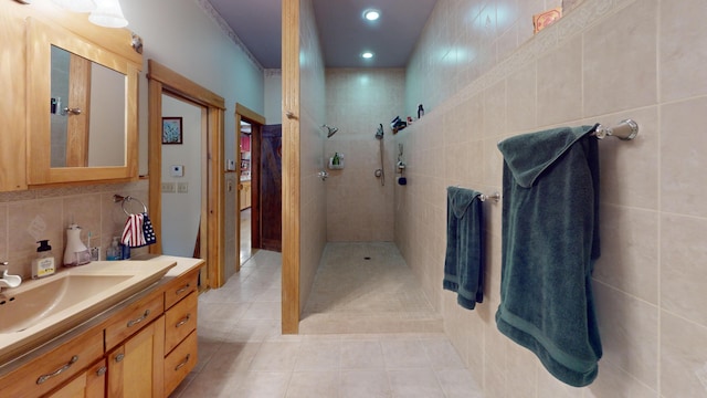 bathroom featuring tile patterned flooring, backsplash, tile walls, vanity, and a tile shower