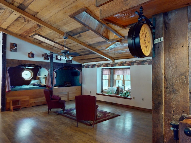 living room with ceiling fan, wood-type flooring, vaulted ceiling with skylight, and wooden ceiling