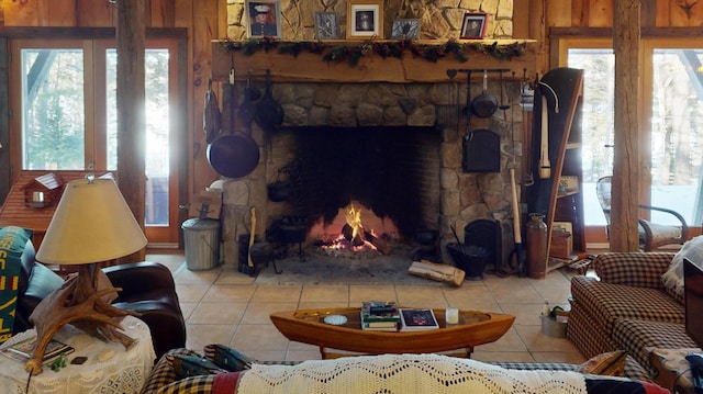 living room featuring a stone fireplace, light tile patterned floors, and wooden walls