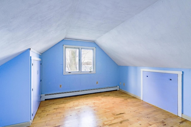 additional living space with baseboard heating, light hardwood / wood-style floors, and lofted ceiling