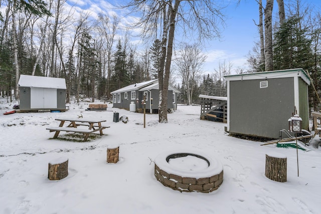 yard covered in snow with a storage unit and an outdoor fire pit