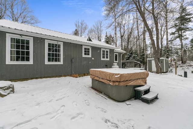 snow covered back of property featuring a shed