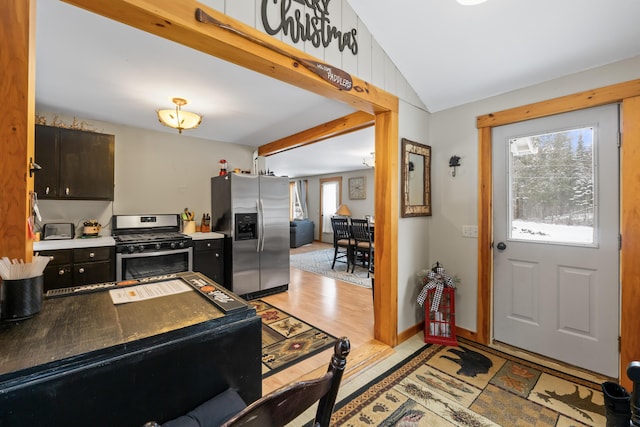 interior space with lofted ceiling, light hardwood / wood-style floors, dark brown cabinetry, and appliances with stainless steel finishes