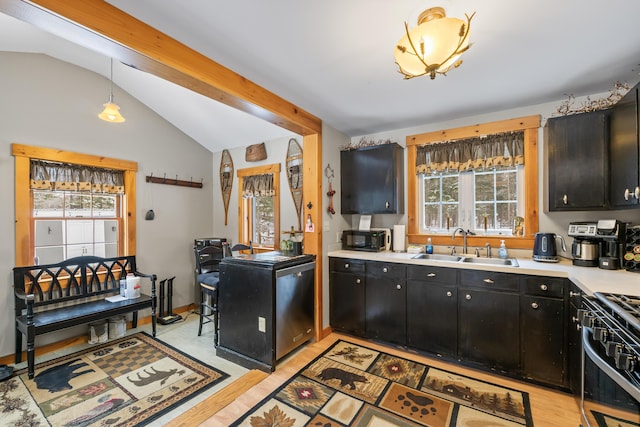 kitchen featuring vaulted ceiling with beams, decorative light fixtures, sink, and a wealth of natural light