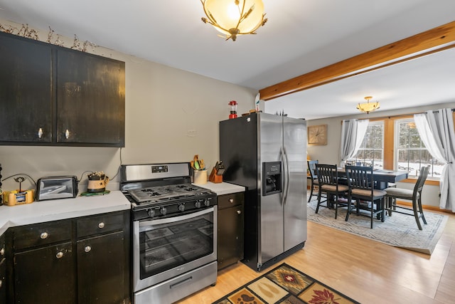 kitchen with beamed ceiling, light wood-type flooring, and stainless steel appliances