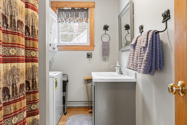 bathroom with hardwood / wood-style floors, vanity, and stacked washing maching and dryer