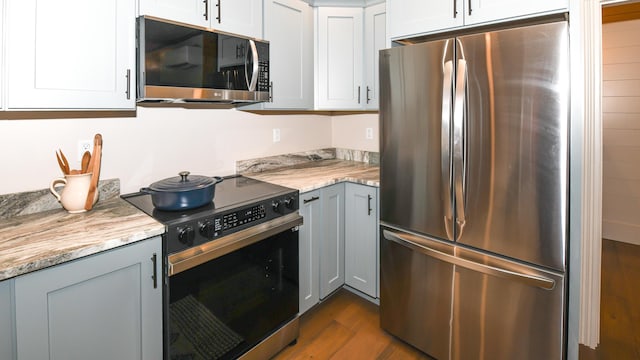 20 N High St, Bridgton, ME 04009 - kitchen with light stone countertops, white cabinets, hardwood / wood-style flooring, and appliances with stainless steel finishes