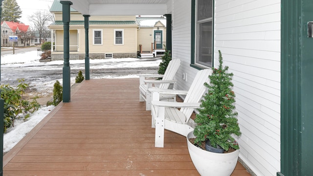 snow covered deck featuring covered porch