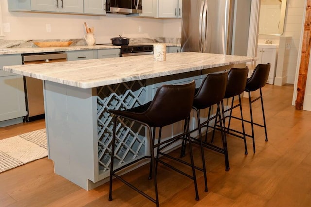 20 N High St, Bridgton, ME 04009 - kitchen featuring appliances with stainless steel finishes, light wood-type flooring, a kitchen breakfast bar, light stone counters, and a center island