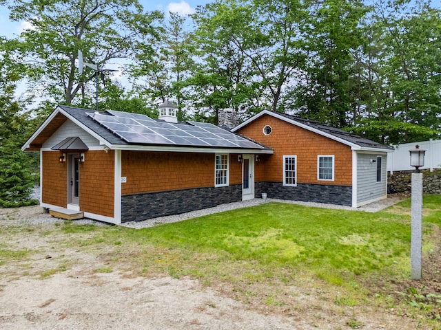 18 Severin Way, Limerick, ME 04048 - view of front facade with roof mounted solar panels, a front yard, stone siding, and a chimney
