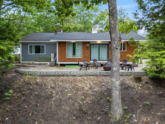 18 Severin Way, Limerick, ME 04048 - view of front facade featuring a chimney, a shingled roof, a patio, and a fire pit