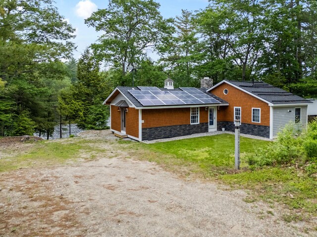 18 Severin Way, Limerick, ME 04048 - view of front of home featuring a chimney, solar panels, stone siding, a front yard, and driveway