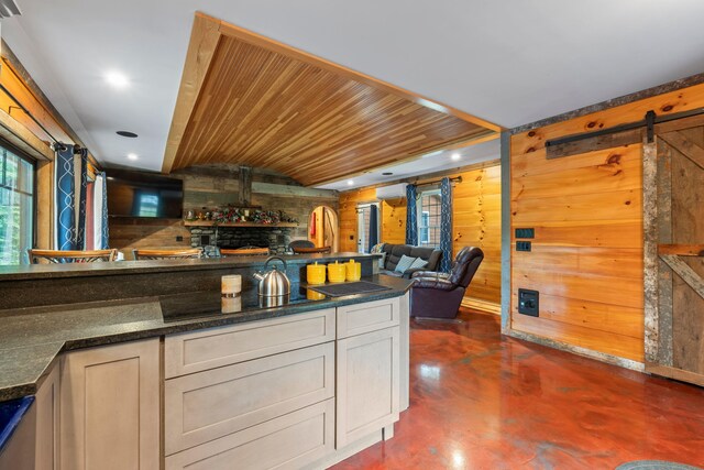 18 Severin Way, Limerick, ME 04048 - kitchen featuring finished concrete flooring, a barn door, an AC wall unit, black electric cooktop, and wooden walls