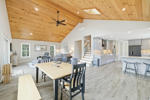 dining area featuring ceiling fan, a skylight, light hardwood / wood-style floors, and wooden ceiling