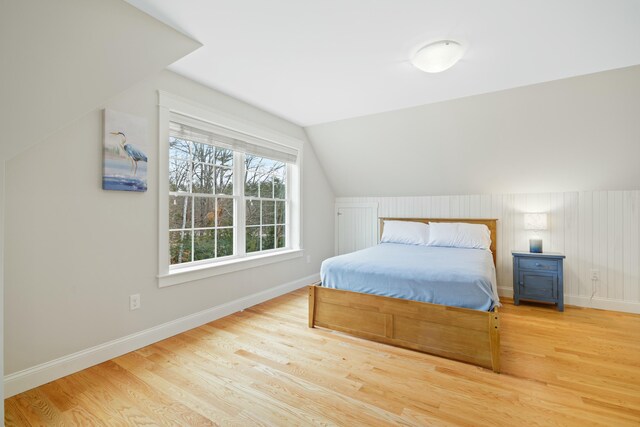 bedroom with light wood-type flooring and vaulted ceiling