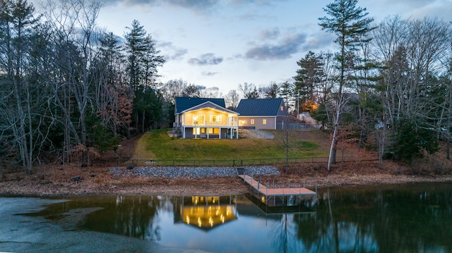 rear view of property featuring a lawn and a water view