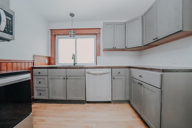 kitchen with pendant lighting, sink, gray cabinets, light hardwood / wood-style floors, and stainless steel appliances