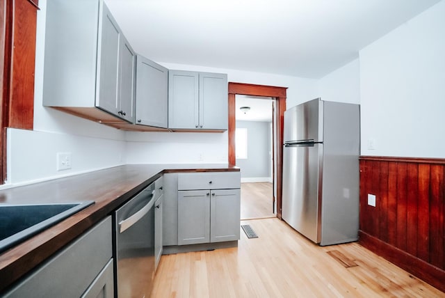 kitchen featuring wooden counters, stainless steel appliances, gray cabinets, and light hardwood / wood-style flooring