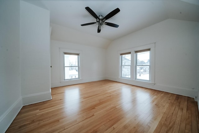 spare room featuring plenty of natural light, light wood-type flooring, and vaulted ceiling