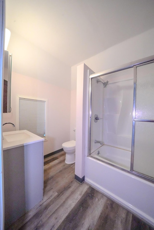 full bathroom featuring vanity, toilet, wood-type flooring, and bath / shower combo with glass door