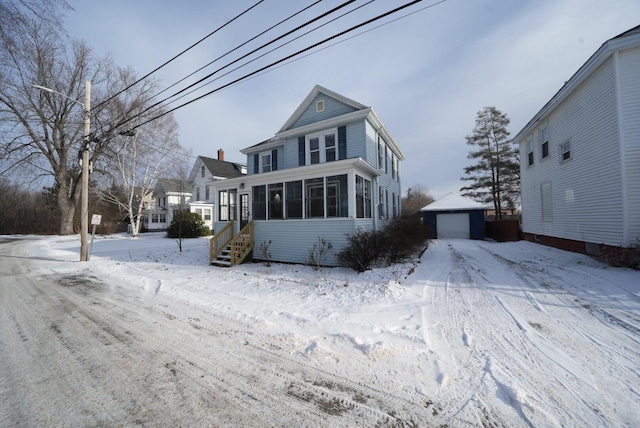 view of front of house featuring a sunroom, a garage, and an outdoor structure