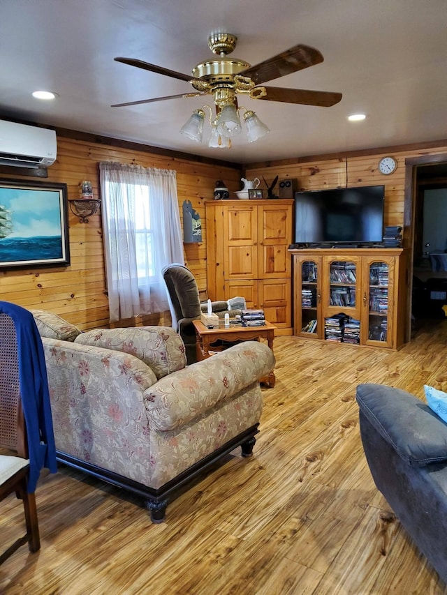 living room featuring a wall mounted air conditioner, ceiling fan, wood walls, and wood-type flooring