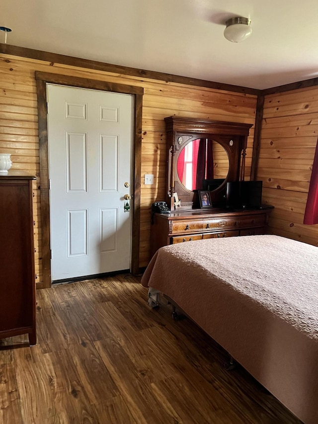 bedroom with dark wood-type flooring and wooden walls