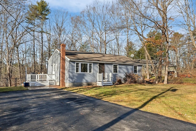 ranch-style house featuring a wooden deck and a front lawn