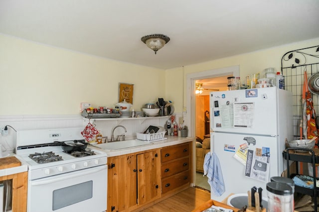 kitchen featuring white appliances, sink, and light hardwood / wood-style flooring