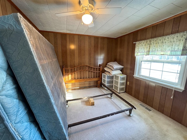 unfurnished bedroom featuring carpet, ceiling fan, and wood walls