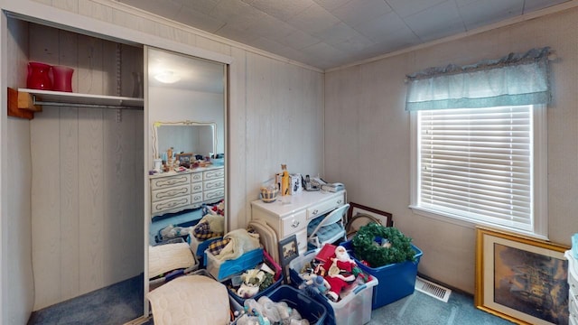 carpeted bedroom featuring wood walls, a closet, and ornamental molding