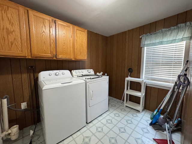 clothes washing area with cabinets, washing machine and dryer, and wood walls