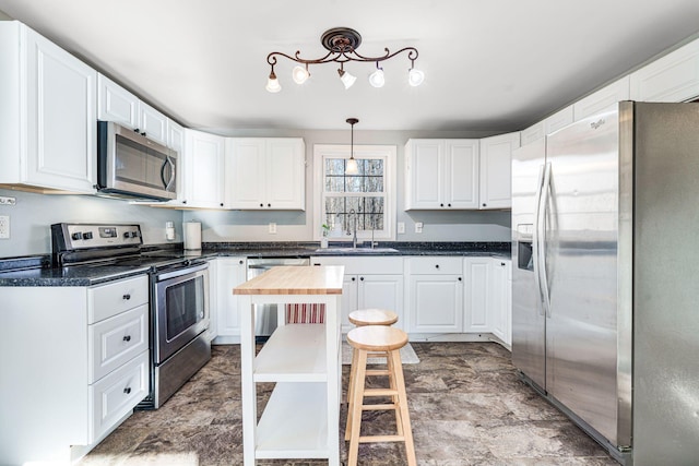 kitchen featuring appliances with stainless steel finishes, white cabinetry, pendant lighting, and sink