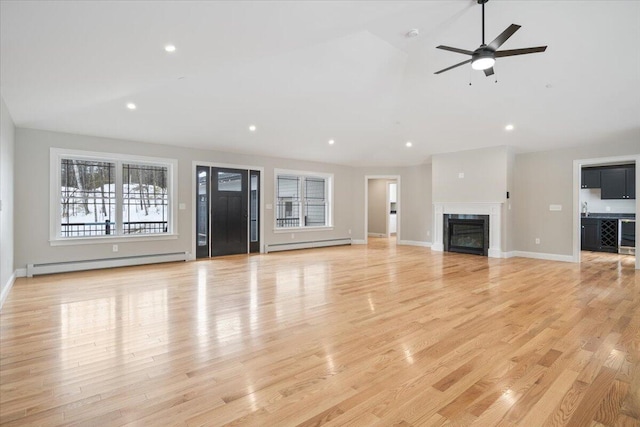 unfurnished living room featuring a glass covered fireplace, light wood-style flooring, and baseboard heating