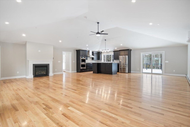 unfurnished living room featuring lofted ceiling, recessed lighting, light wood-style floors, a glass covered fireplace, and a ceiling fan