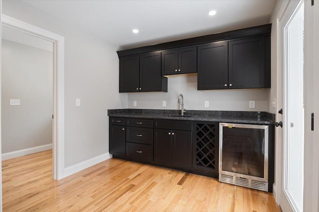 bar featuring wine cooler, recessed lighting, a sink, baseboards, and light wood-type flooring