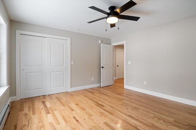 unfurnished bedroom with ceiling fan, a baseboard heating unit, baseboards, a closet, and light wood finished floors