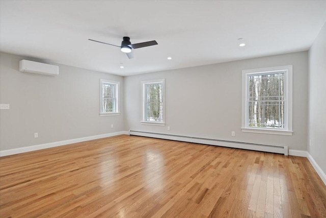 unfurnished room featuring a ceiling fan, baseboards, light wood-style floors, an AC wall unit, and baseboard heating