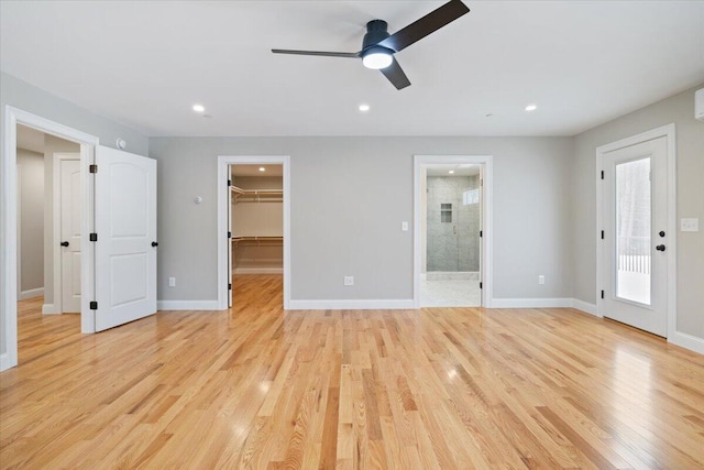 unfurnished bedroom featuring ensuite bathroom, recessed lighting, baseboards, light wood finished floors, and a walk in closet