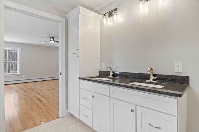 bathroom featuring a baseboard heating unit, double vanity, a sink, and wood finished floors