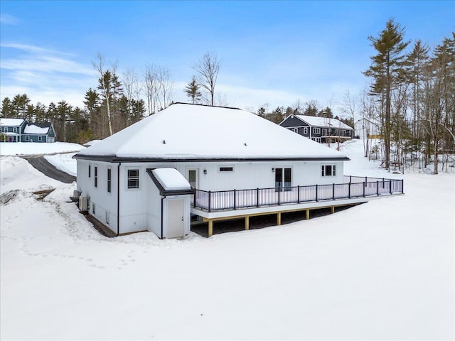 snow covered back of property featuring a deck