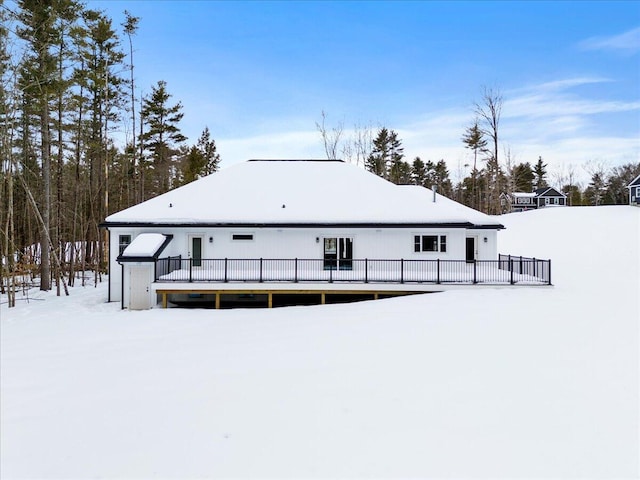 snow covered back of property featuring a wooden deck