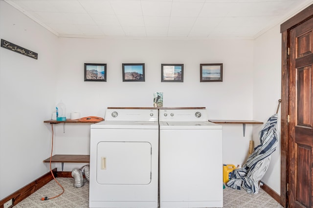 laundry area with light colored carpet, washer and dryer, and ornamental molding