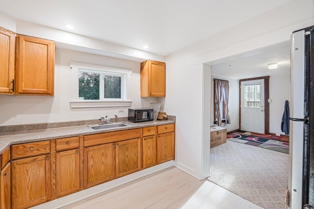 kitchen featuring white fridge, light hardwood / wood-style floors, sink, and a wealth of natural light