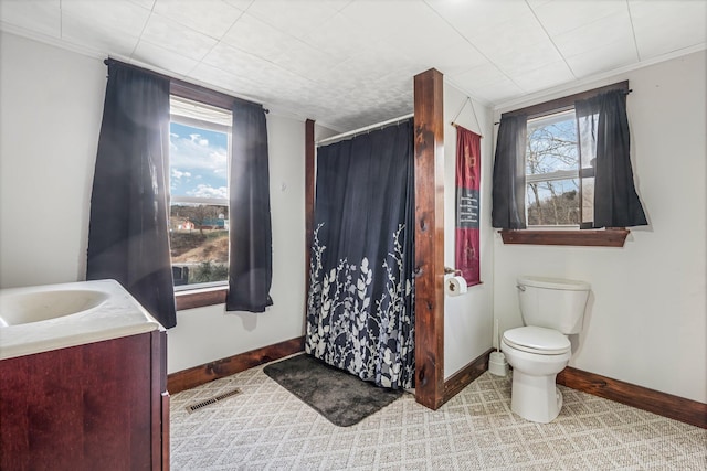 bathroom with walk in shower, plenty of natural light, vanity, and toilet