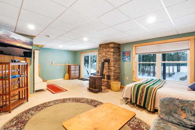 carpeted bedroom with a wood stove and a paneled ceiling