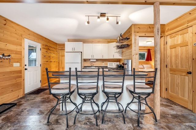 kitchen featuring wooden walls, white cabinets, and white appliances