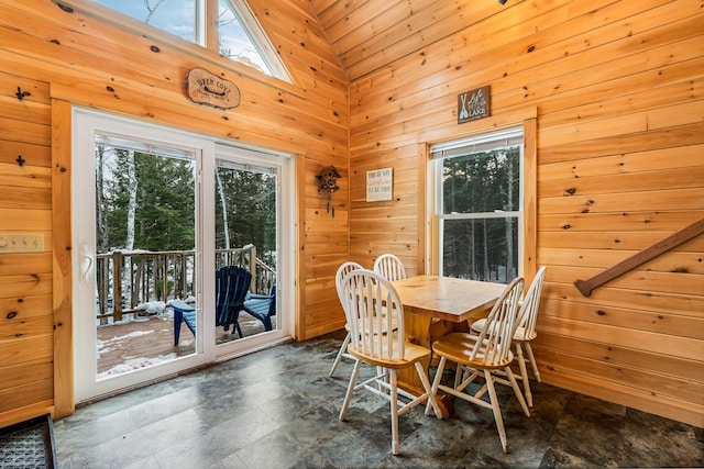 dining room with high vaulted ceiling and wood walls