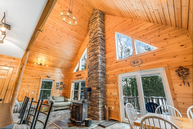 living room featuring wooden walls, a wood stove, wood ceiling, and high vaulted ceiling