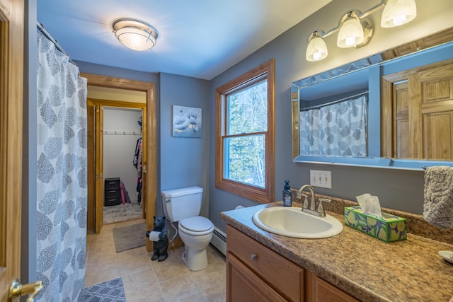 bathroom with toilet, vanity, and a baseboard heating unit